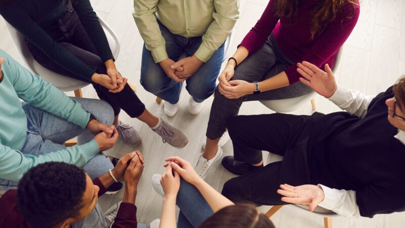 Pessoas reunidas em círculo durante um grupo terapêutico em saúde mental.